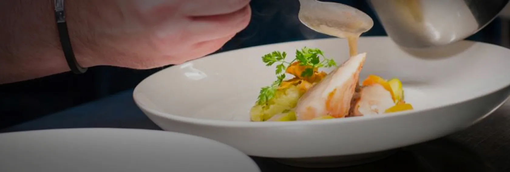 Le chef nappant une assiette gastronomique de sauce