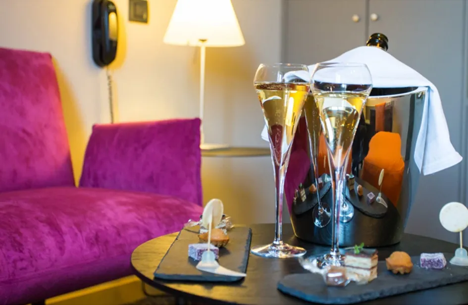 Coupes de champagne et mignardises dans le salon d'une chambre de l'Hôtel du Morvan